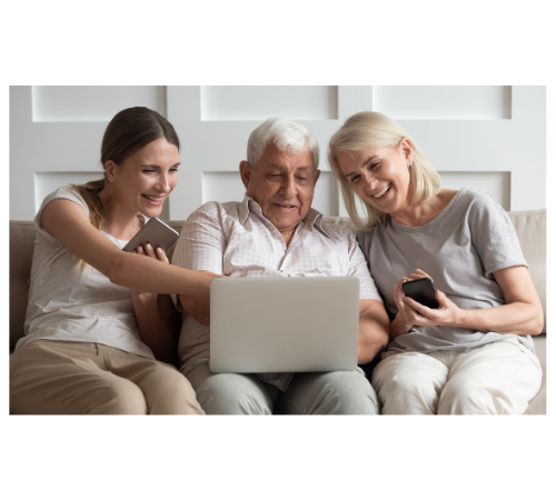 older man sitting on couch looking at laptop next to two women