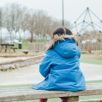 Little girl sitting on bench alone at playground